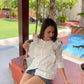 Stylera ladies ruffle sleeve white shirt styled casually with denim shorts in a sunny outdoor setting