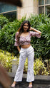 Model wearing ladies trendy summer white pants with a floral crop top in an outdoor setting