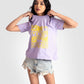 Woman wearing Stylera lavender graphic t-shirt for women with yellow design and denim shorts