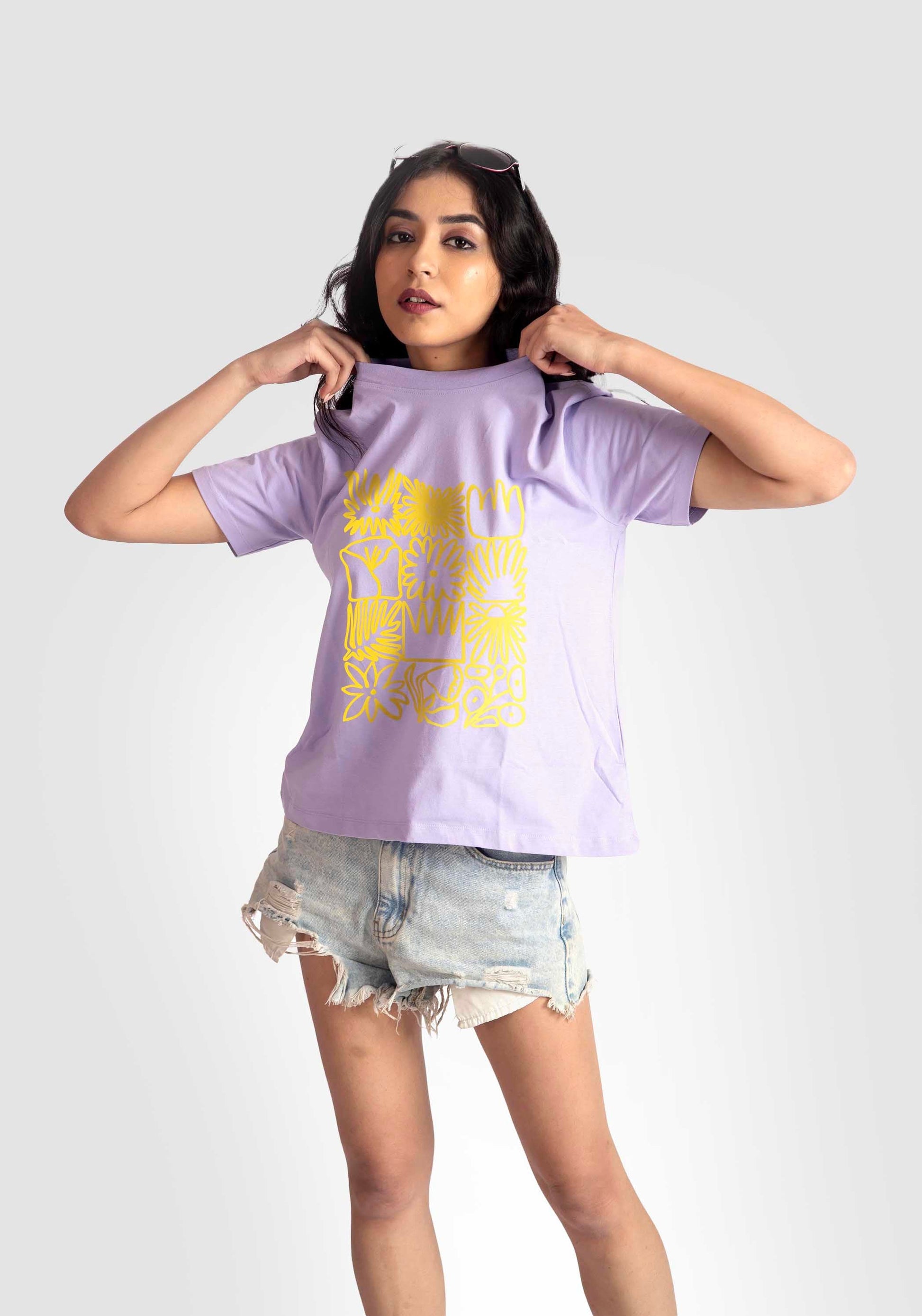 Woman wearing Stylera lavender graphic t-shirt for women with yellow design and denim shorts