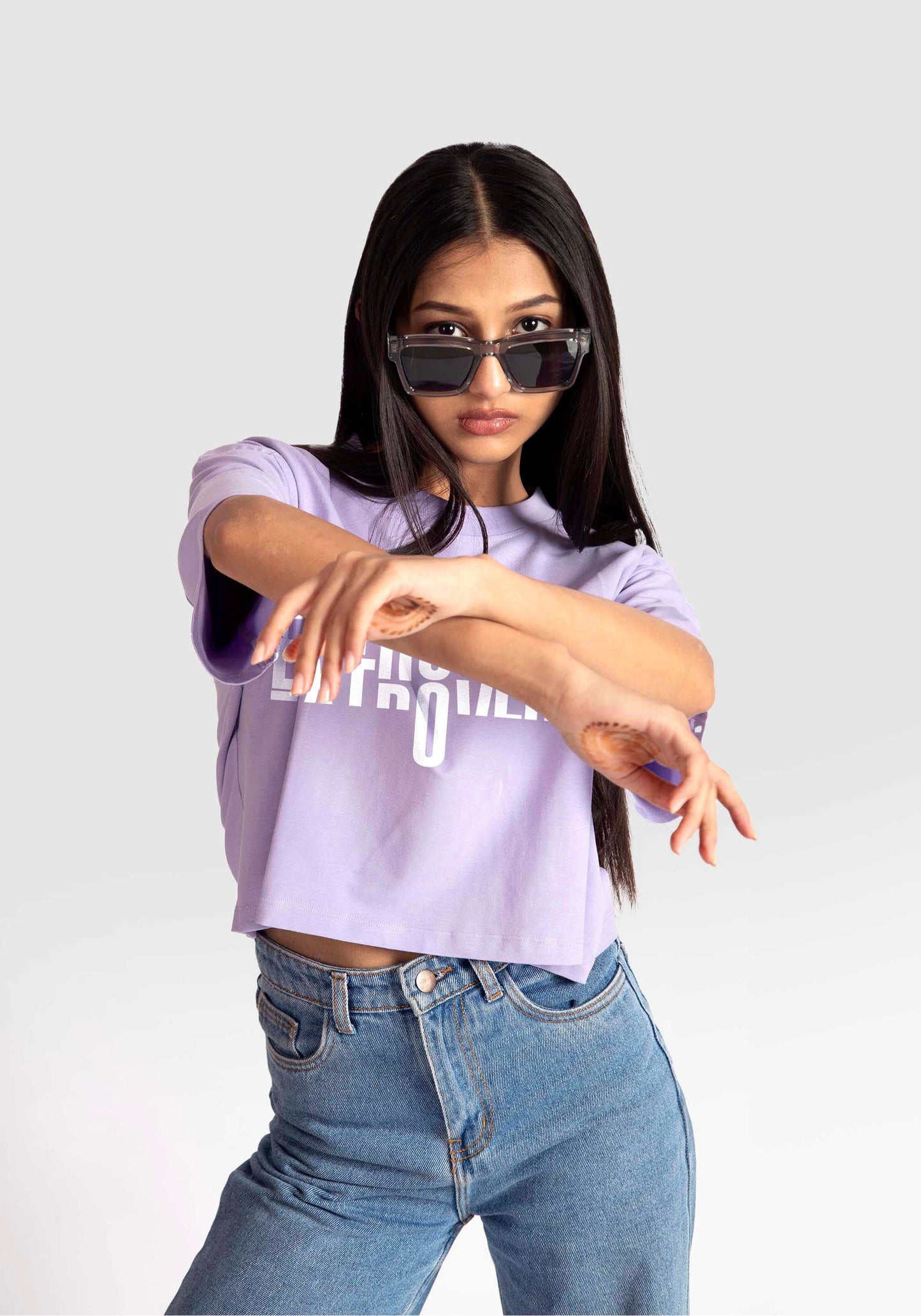 Woman wearing Stylera lavender oversized crop top paired with high-waisted blue jeans and sunglasses