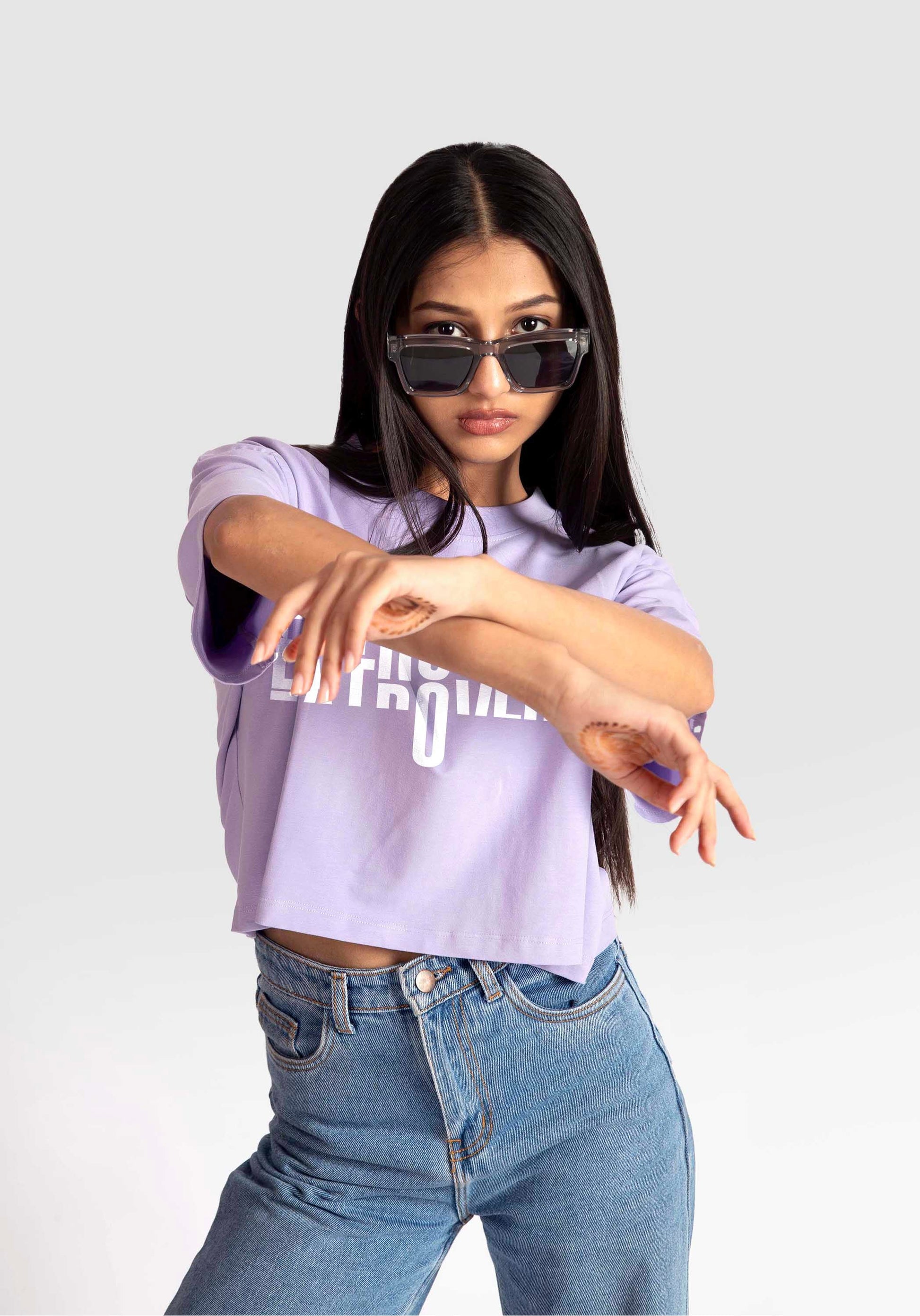 Woman wearing Stylera lavender oversized crop top paired with high-waisted blue jeans and sunglasses