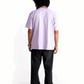 Back view of model wearing Stylera lavender oversized t-shirt paired with black pants