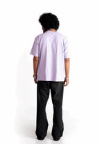 Back view of model wearing Stylera lavender oversized t-shirt paired with black pants