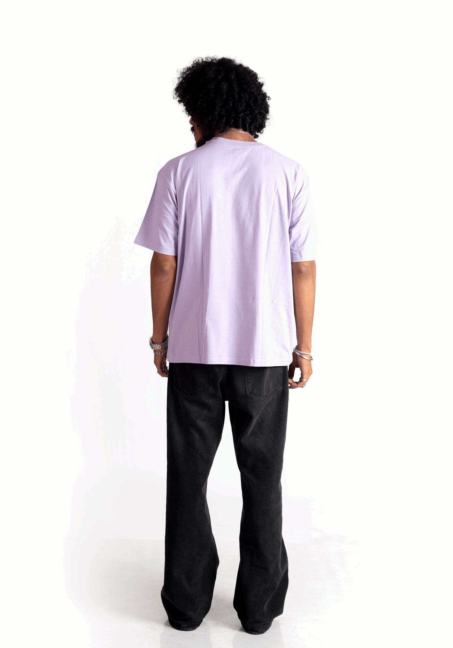 Back view of model wearing Stylera lavender oversized t-shirt paired with black pants