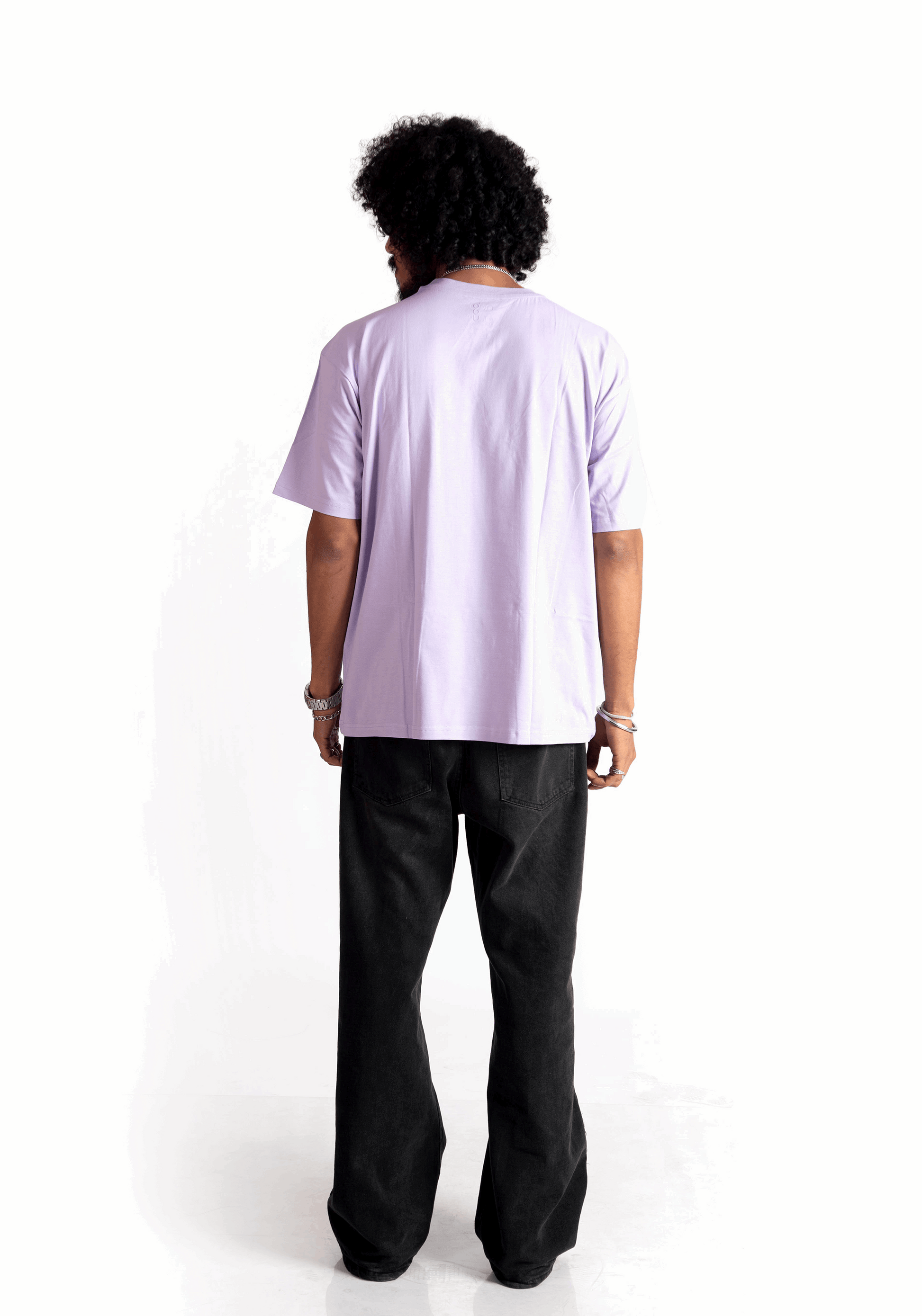 Back view of model wearing Stylera lavender oversized t-shirt paired with black pants