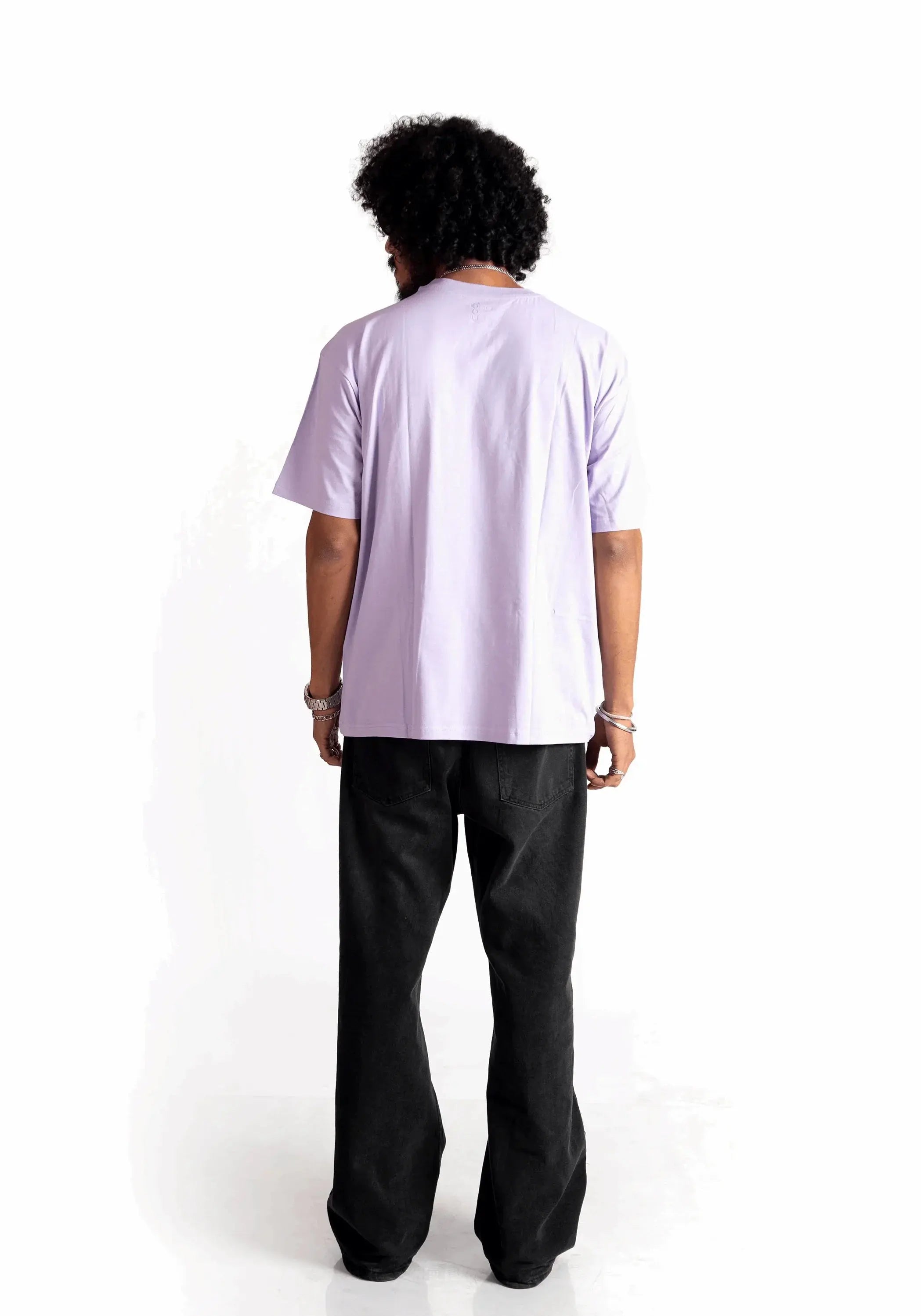 Back view of model wearing Stylera lavender oversized t-shirt paired with black pants