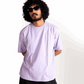Man wearing a lavender oversized t-shirt by Stylera paired with black pants and sunglasses
