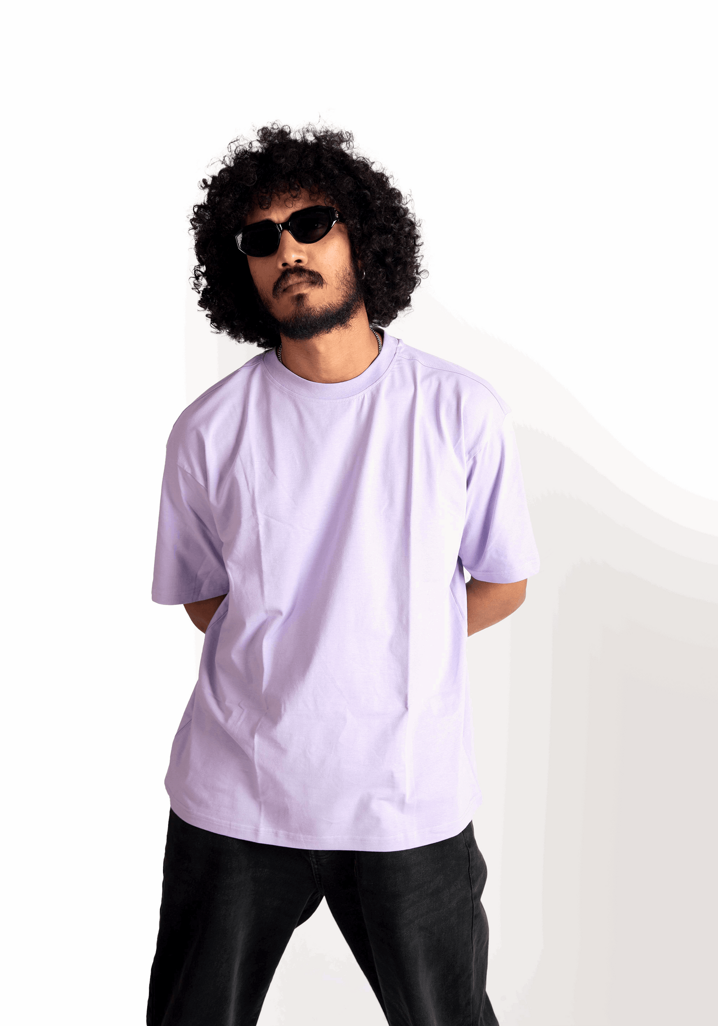 Man wearing a lavender oversized t-shirt by Stylera paired with black pants and sunglasses