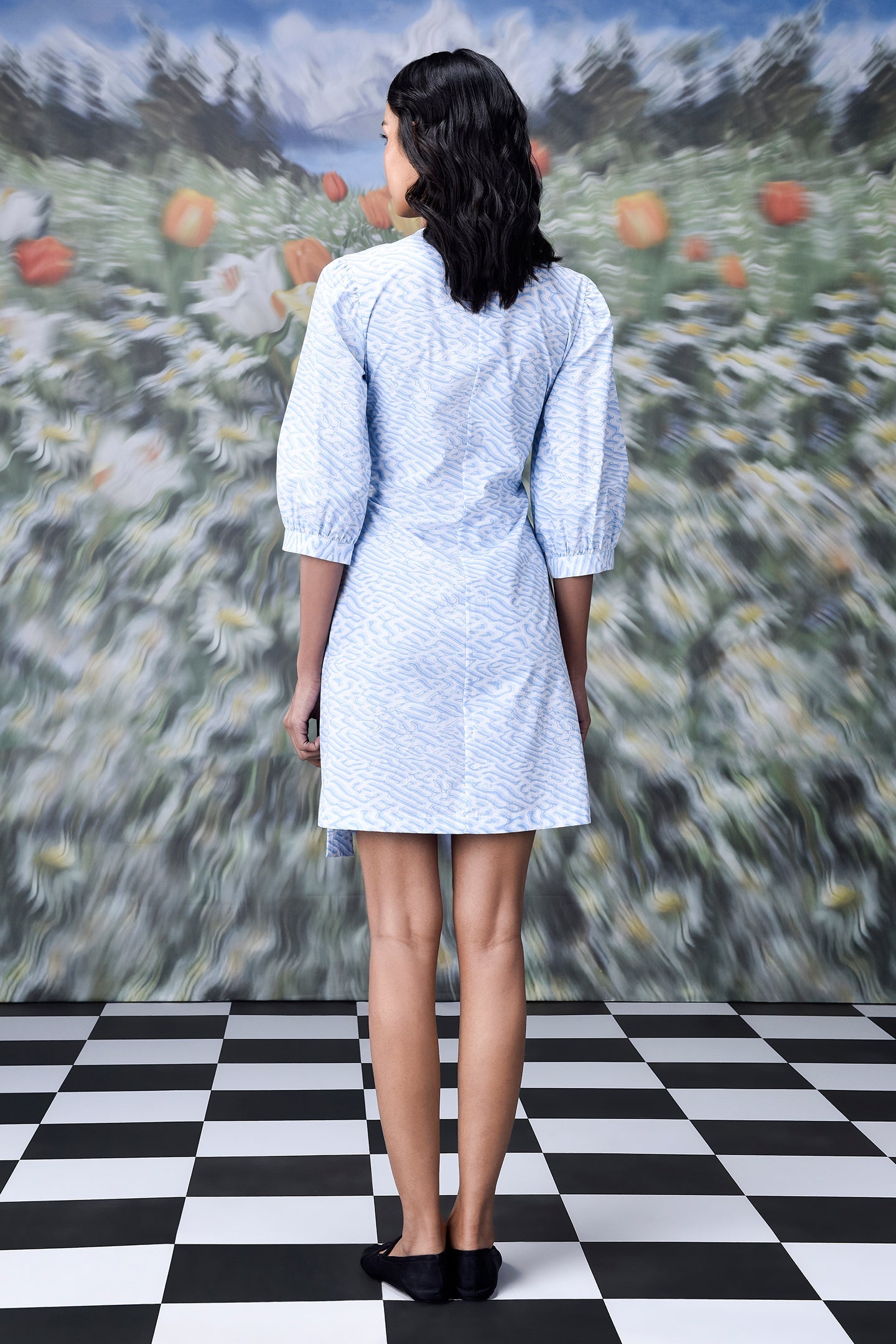 Back view of model wearing light blue wrap dress by Stylera with elbow sleeves