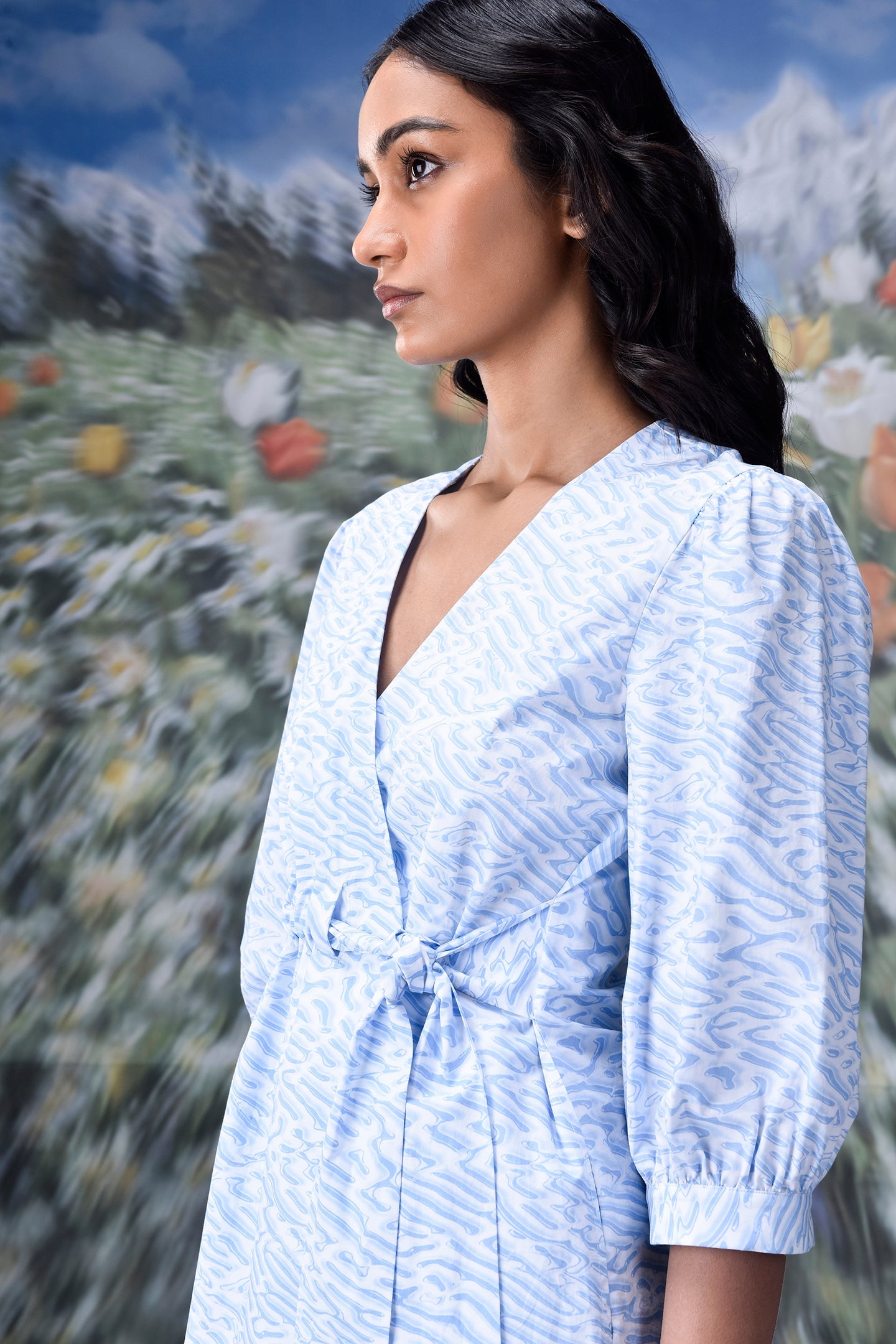 Stylera model wearing light blue wrap dress with puff sleeves tie waist and V neckline