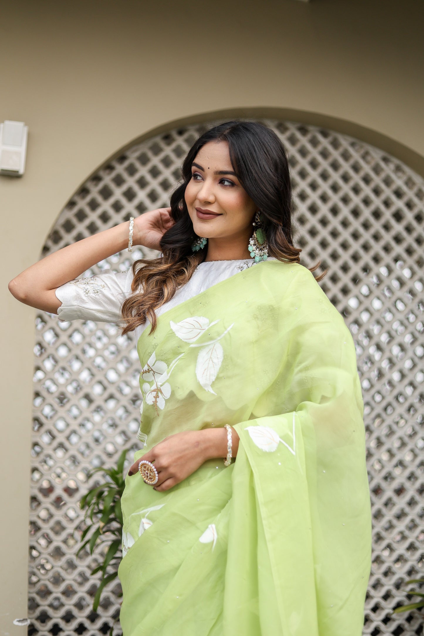 Lightweight party wear saree in green with floral designs, styled elegantly for a festive look