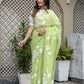 Model wearing a lightweight party wear saree in vibrant green with floral designs and elegant draping