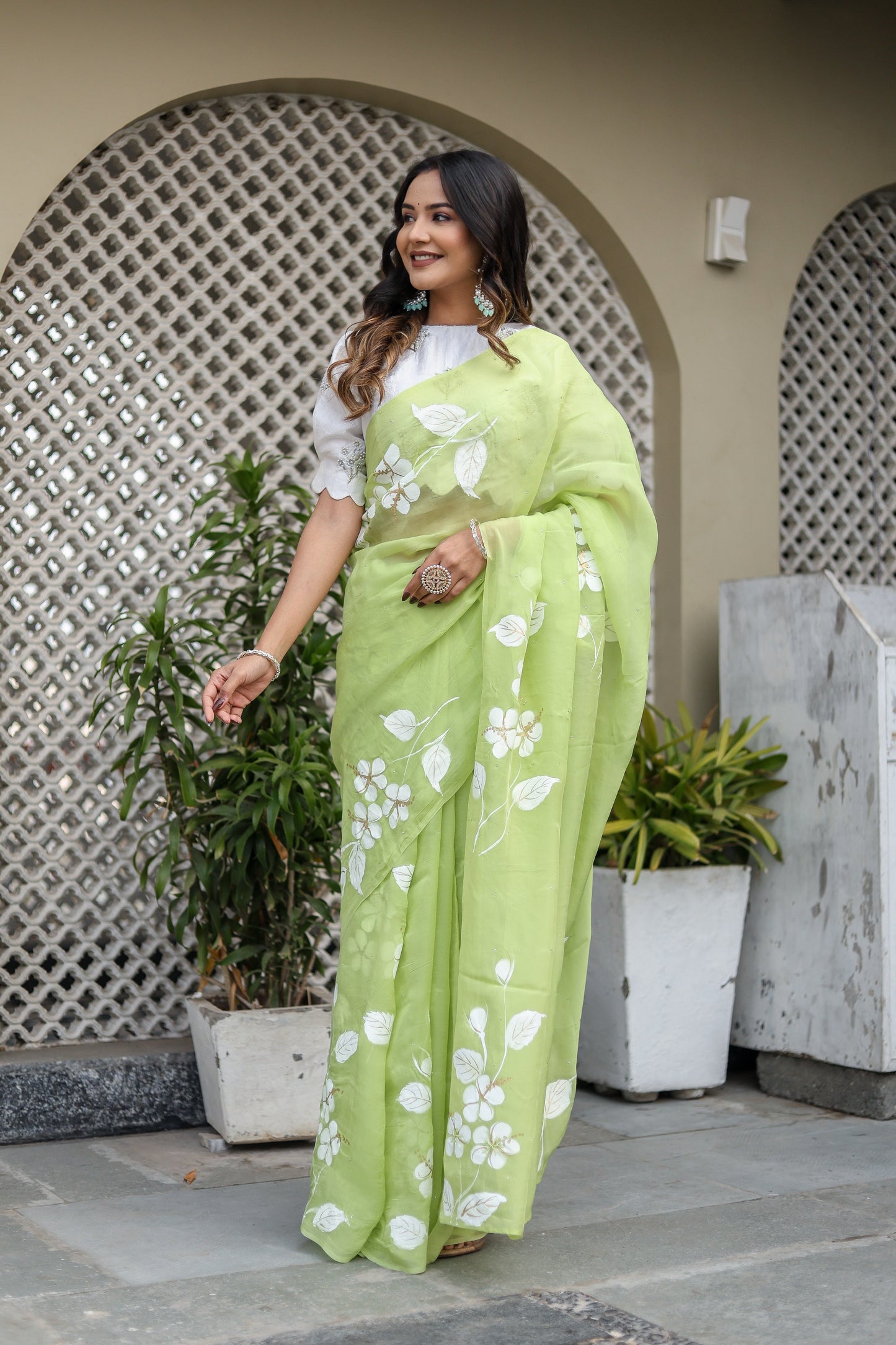 Model wearing a lightweight party wear saree in vibrant green with floral designs and elegant draping