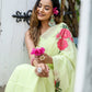 Model wearing a lightweight pastel saree with floral print, sitting gracefully and holding flowers