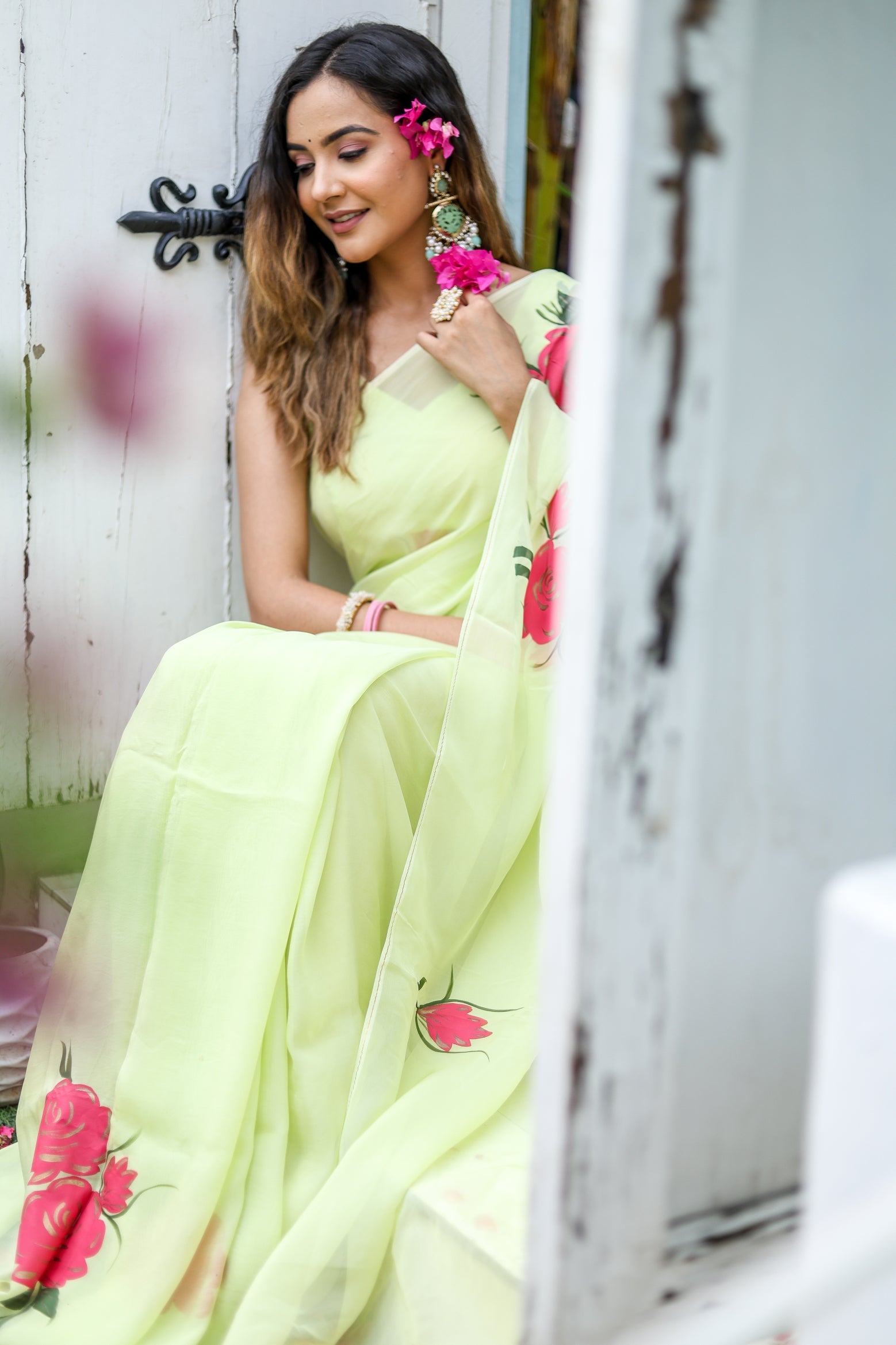 Model wearing a lightweight pastel saree with floral print, styled with accessories and floral accents
