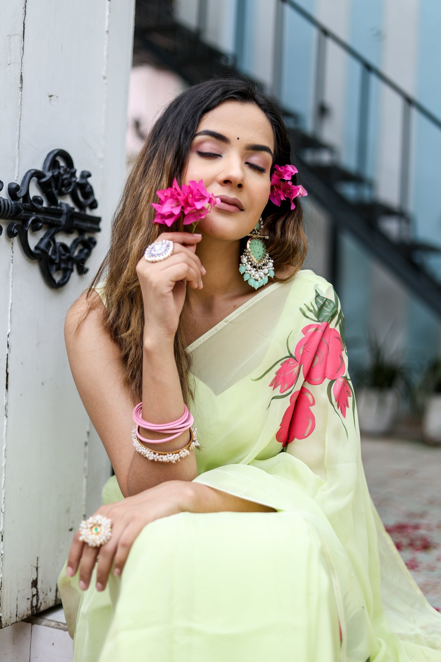 Model wearing a lightweight pastel saree with floral print, paired with jewelry and accessories