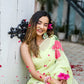 Woman wearing a lightweight pastel saree with floral print, adorned with flower accents in a bright setting