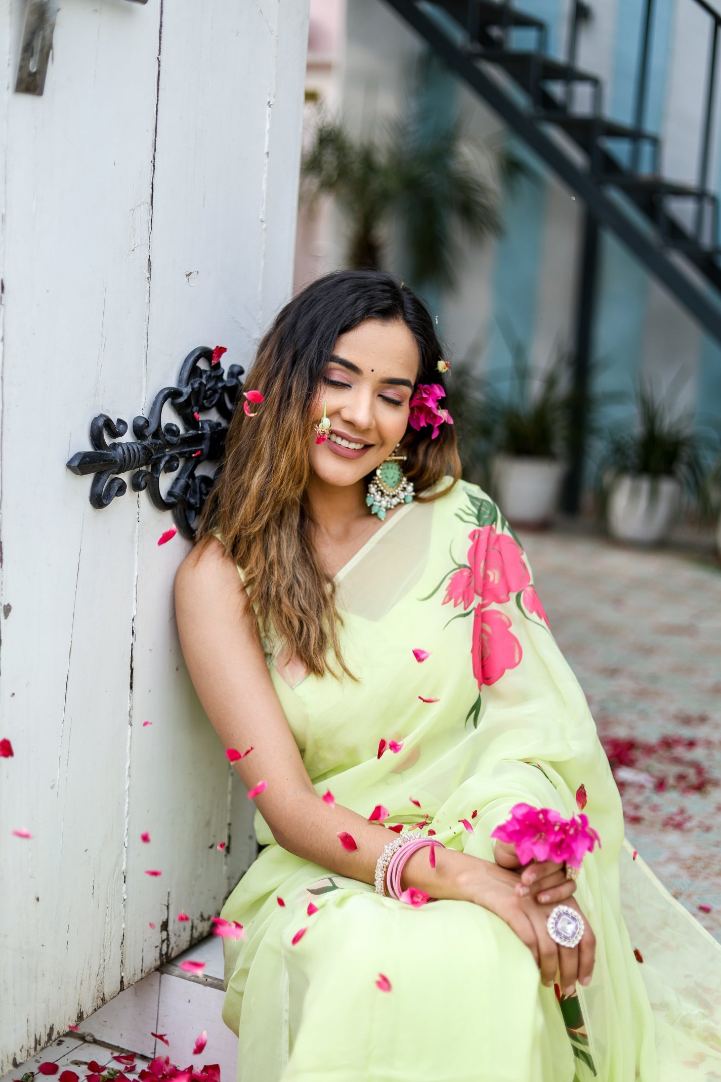 Woman wearing a lightweight pastel saree with floral print, adorned with flower accents in a bright setting
