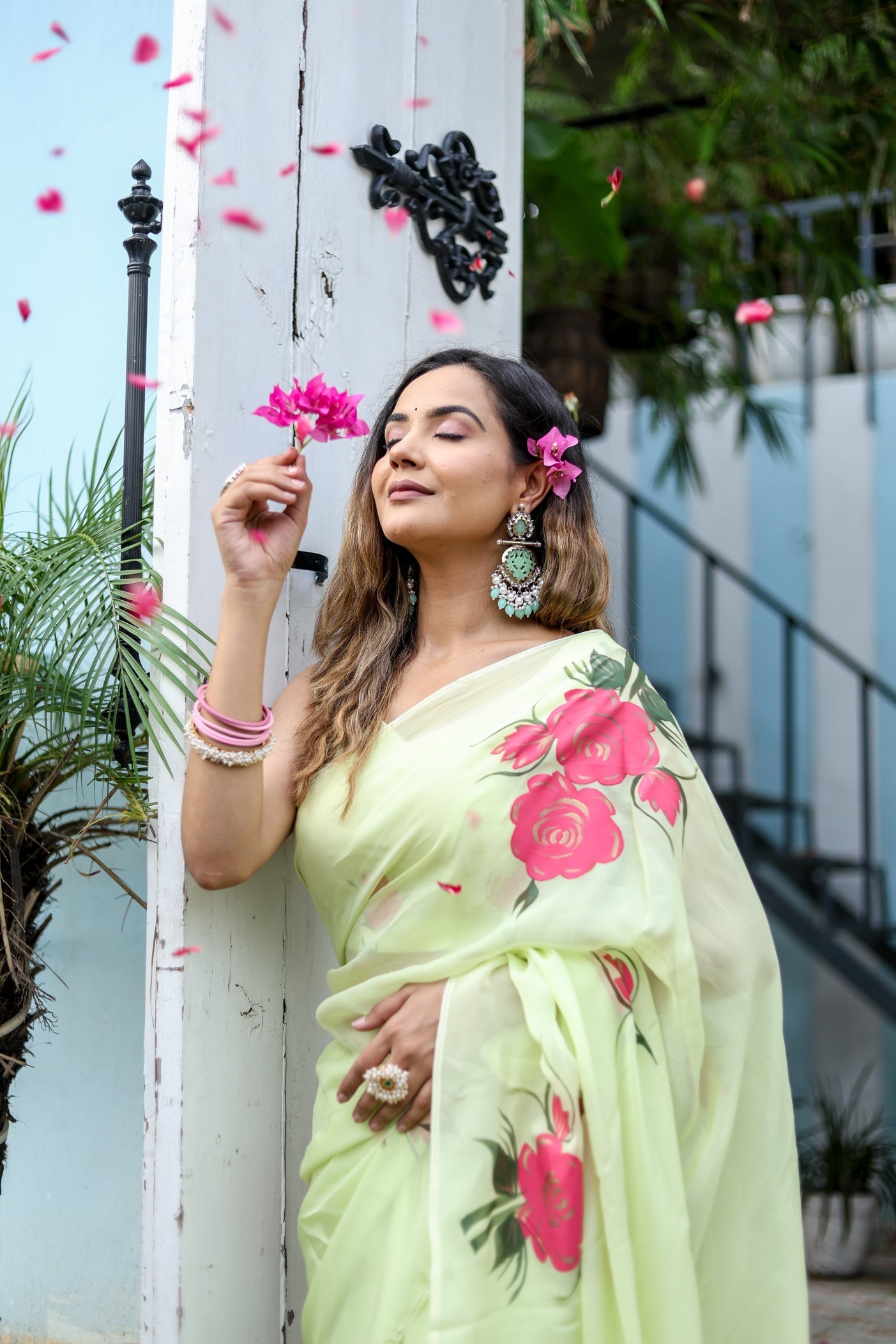 Lightweight pastel saree with floral print worn elegantly by a woman, surrounded by pink flower petals
