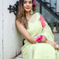 Stylish woman in a lightweight pastel saree with floral print, sitting elegantly with flowers in her hair