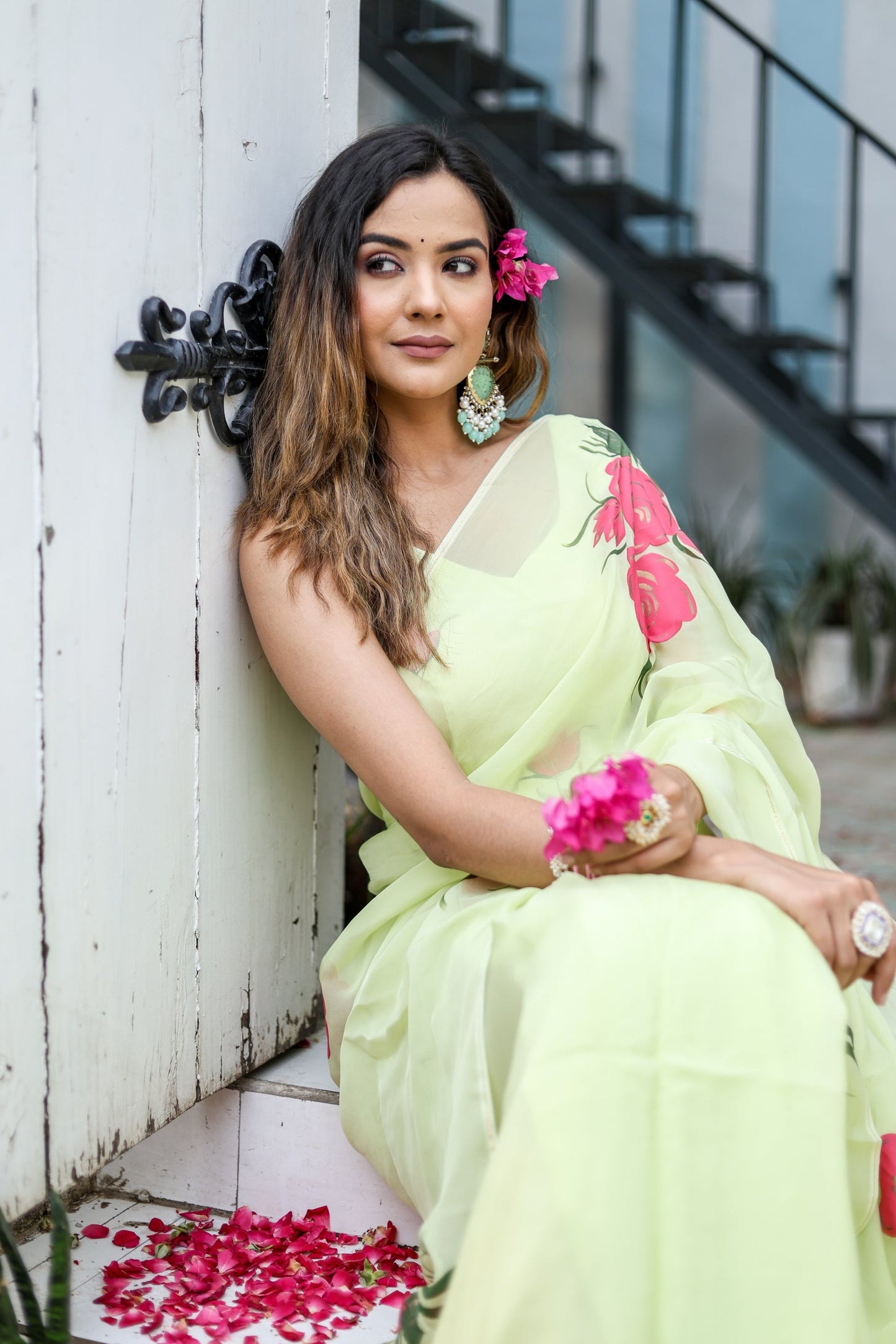 Stylish woman in a lightweight pastel saree with floral print, sitting elegantly with flowers in her hair