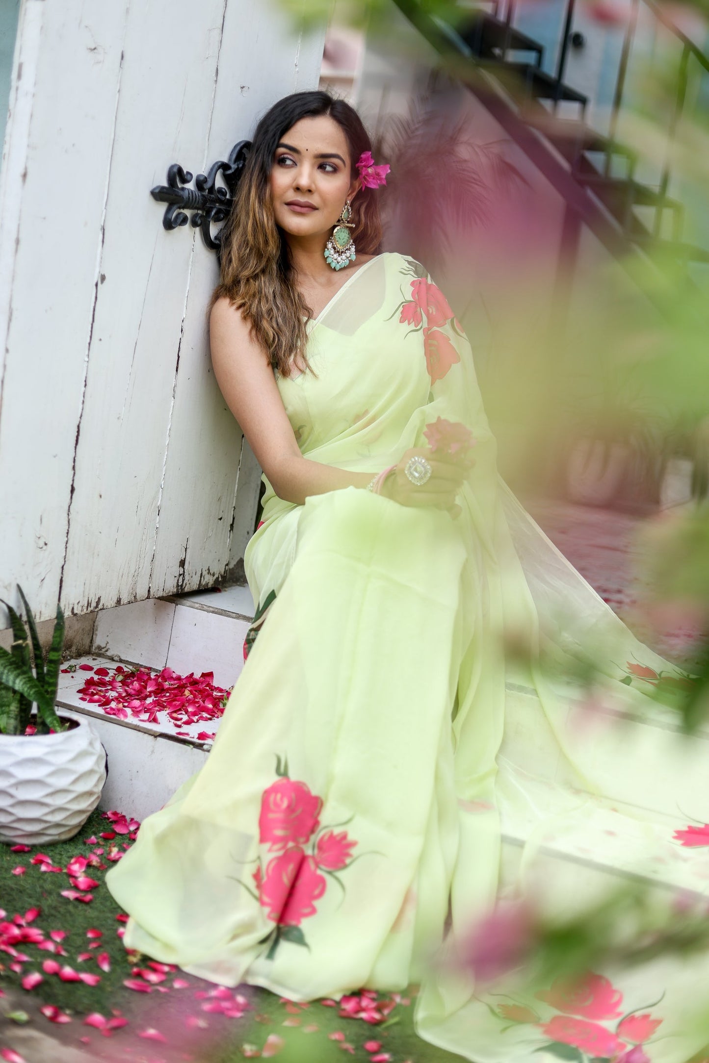 Model wearing a lightweight pastel saree with floral print, styled elegantly with floral accessories