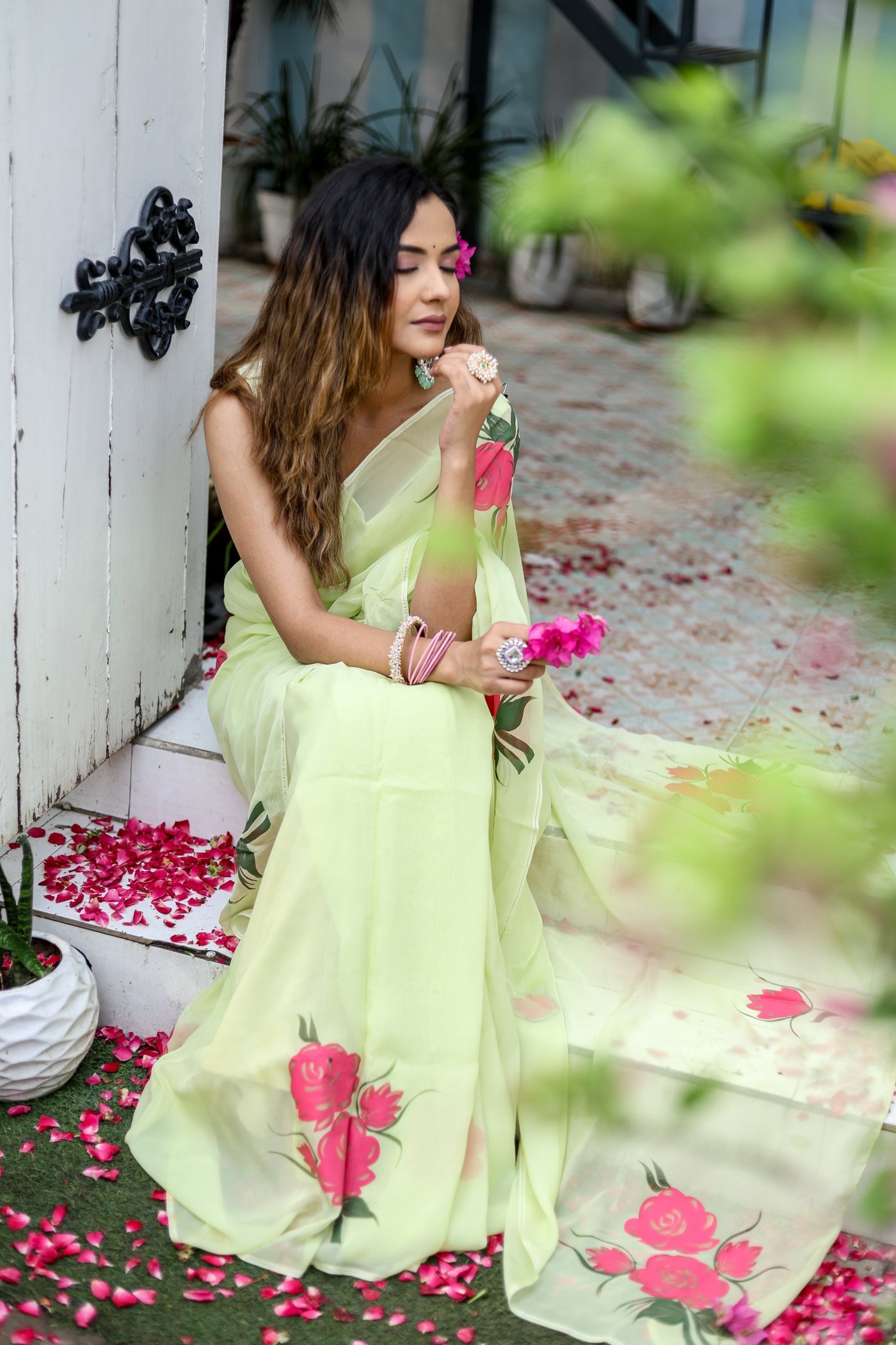 Elegant woman wearing a lightweight pastel saree with floral print sitting gracefully on stairs