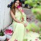 Model wearing a lightweight pastel saree with floral print, sitting among flowers and greenery