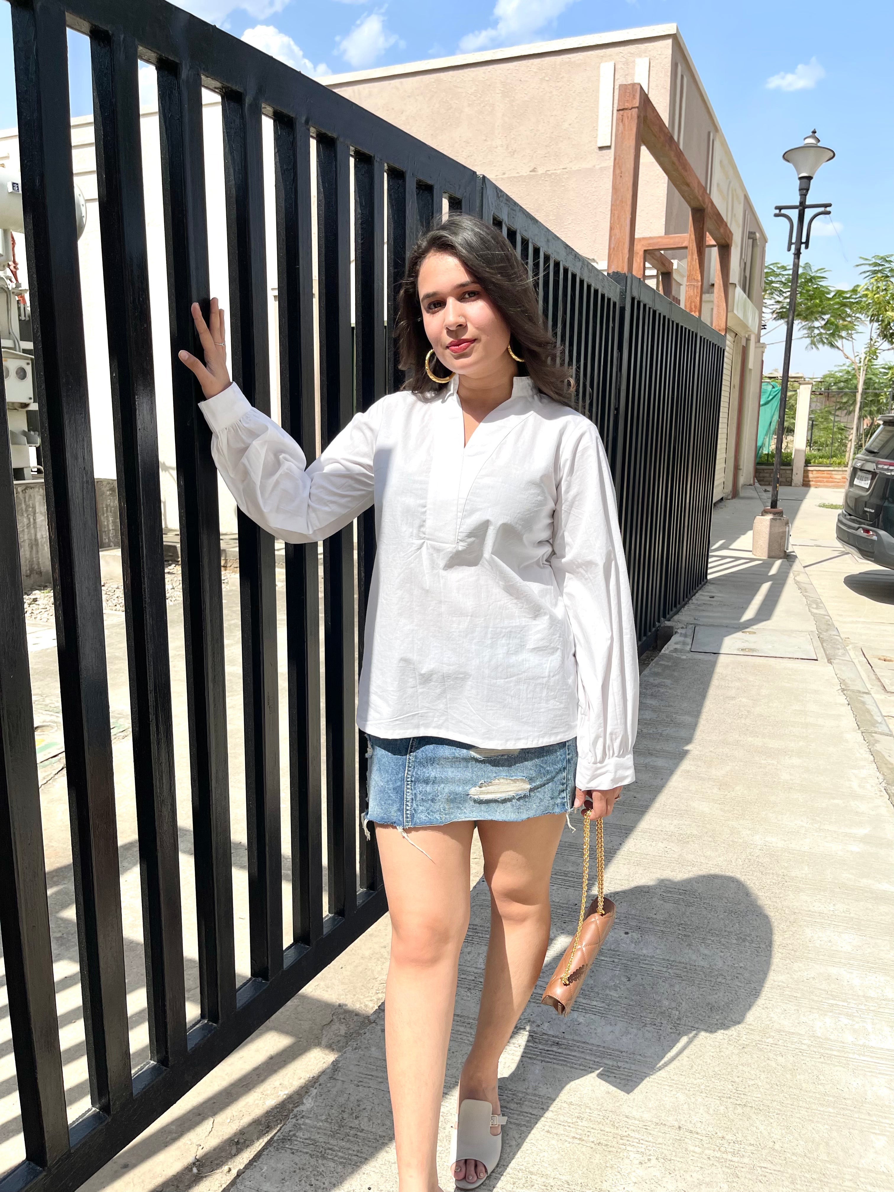 Stylish woman wearing a lightweight white long sleeve top with casual denim skirt and sandals