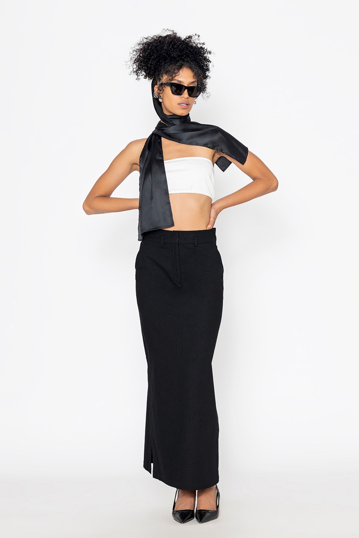 Stylera long black skirt with slit paired with white crop top and black scarf