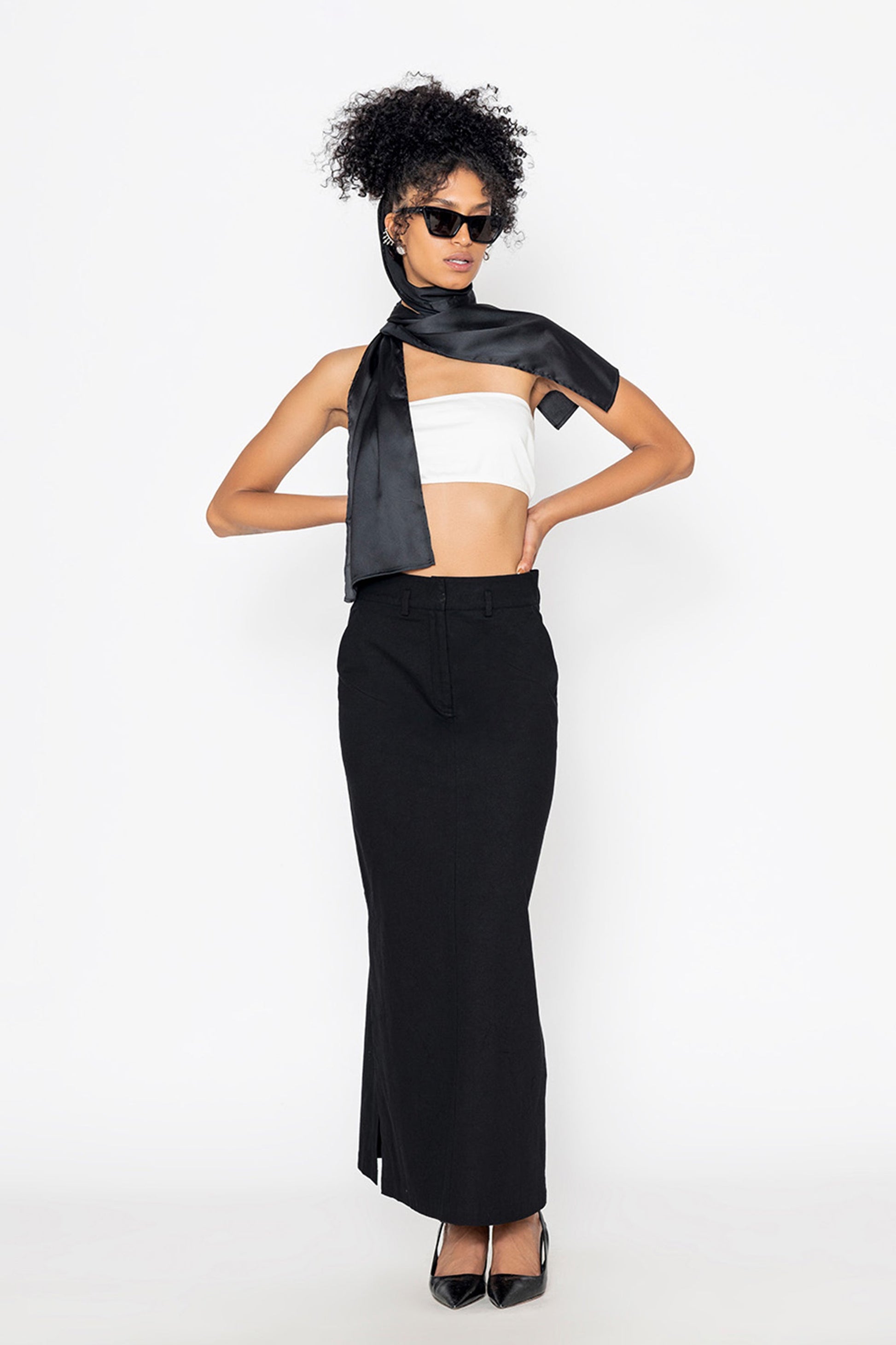 Stylera long black skirt with slit paired with white crop top and black scarf