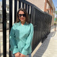 Women wearing a teal long sleeve lightweight top for women paired with denim shorts and sunglasses