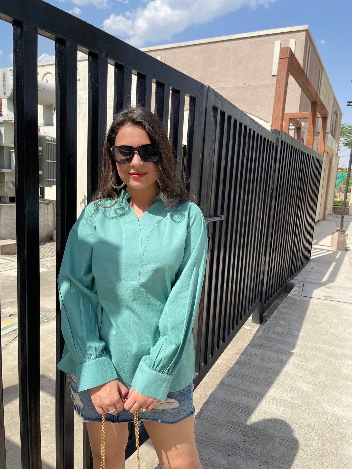 Women wearing a teal long sleeve lightweight top for women paired with denim shorts and sunglasses
