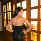 Back view of model wearing Luna Top for women black strapless top and sequined skirt by Stylera near wooden doors