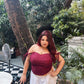 Model in a red lace corset top for women paired with white skirt in outdoor garden setting