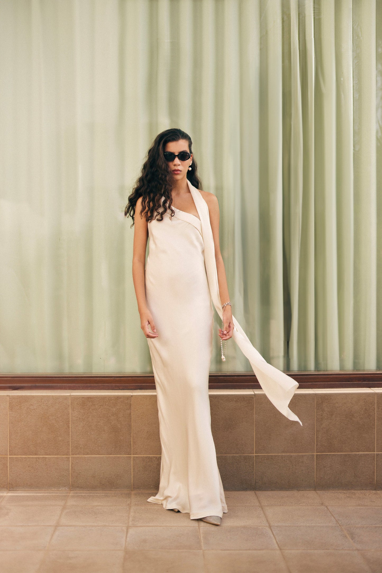 Stylera luxury long gown in cream satin with halter neck and flowing scarf detail