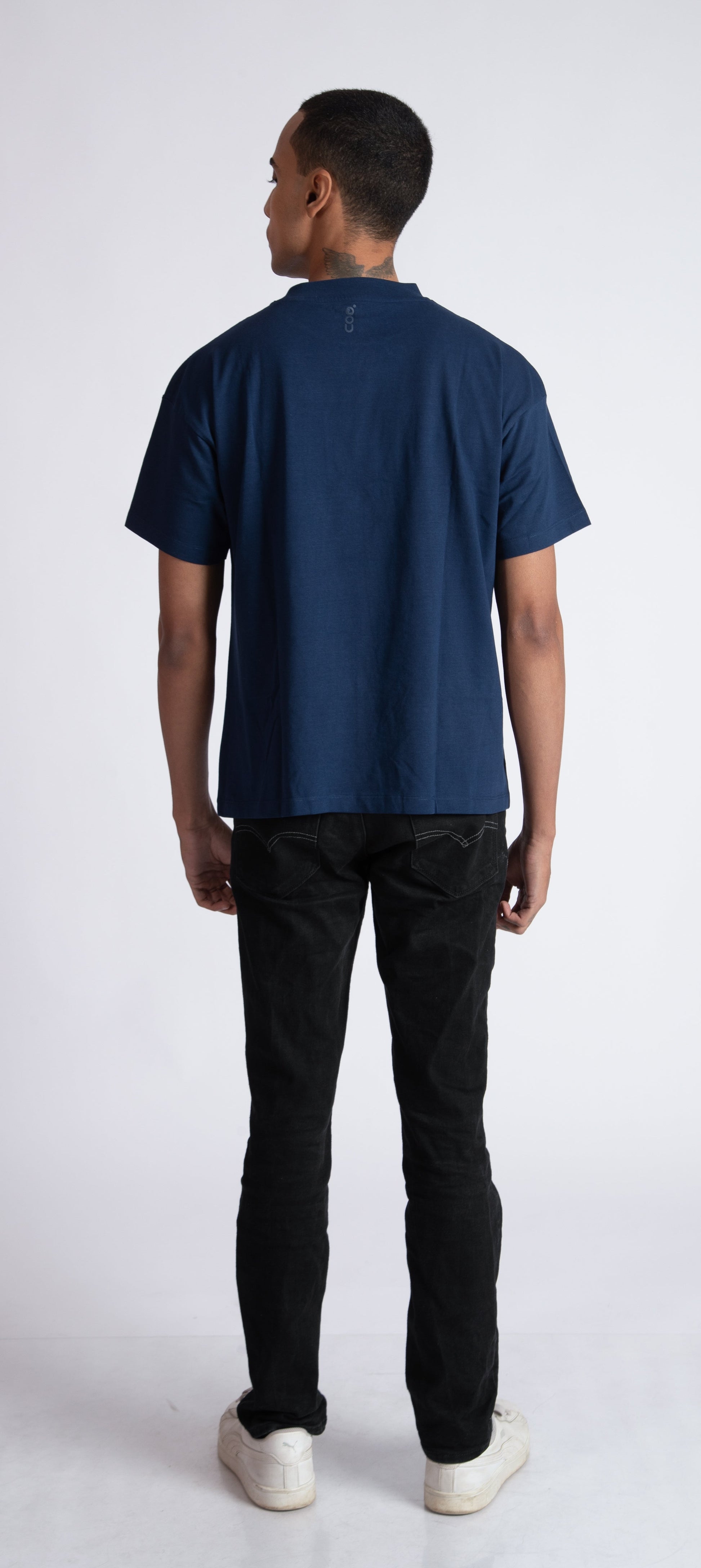 Back view of a man wearing Stylera men's blue regular fit t-shirt with black pants and white shoes