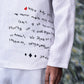 Close-up of Stylera mens linen statement shirt with black handwritten text design on white fabric