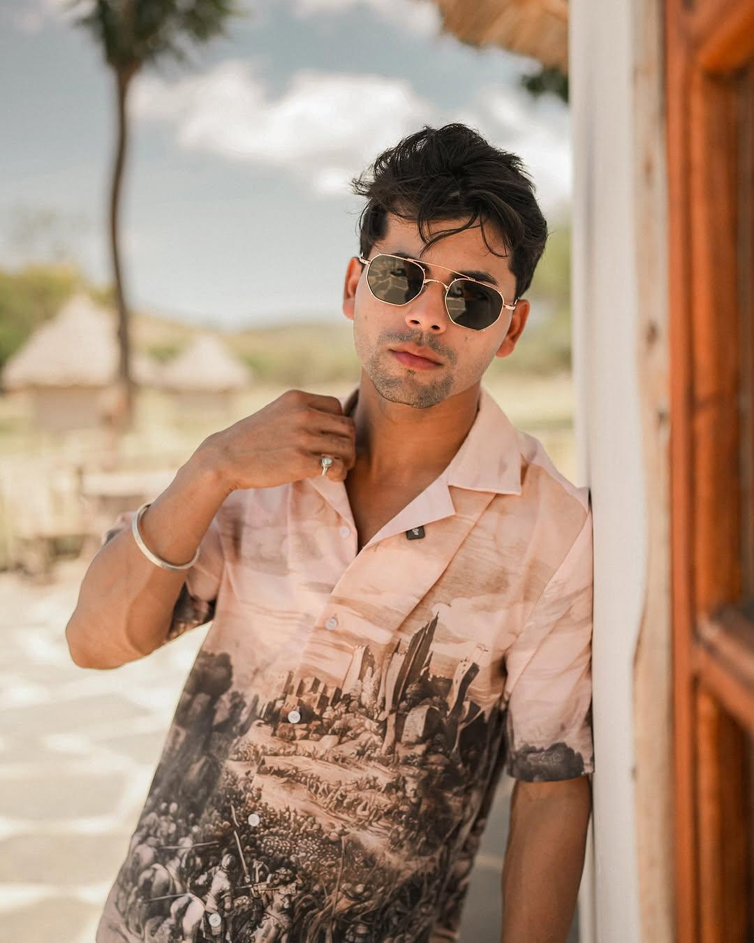 Model wearing Stylera men's printed casual button up shirt in pink with scenic print short sleeve resort style