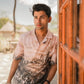 Stylera men's printed casual button up shirt in beige with cityscape print worn by model leaning on wooden door