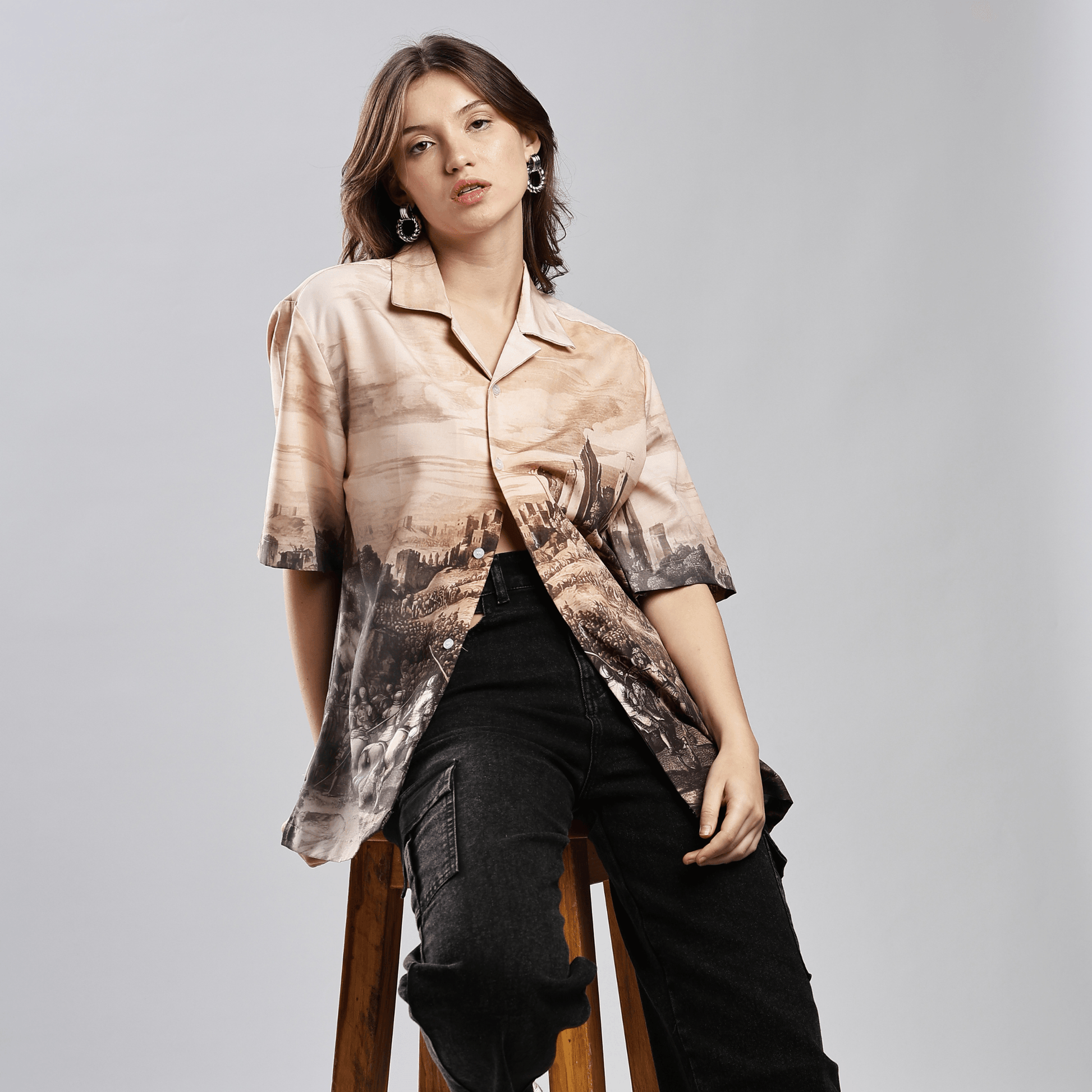 Female model wearing Stylera men's printed casual button up shirt in beige landscape print with short sleeves and relaxed fit