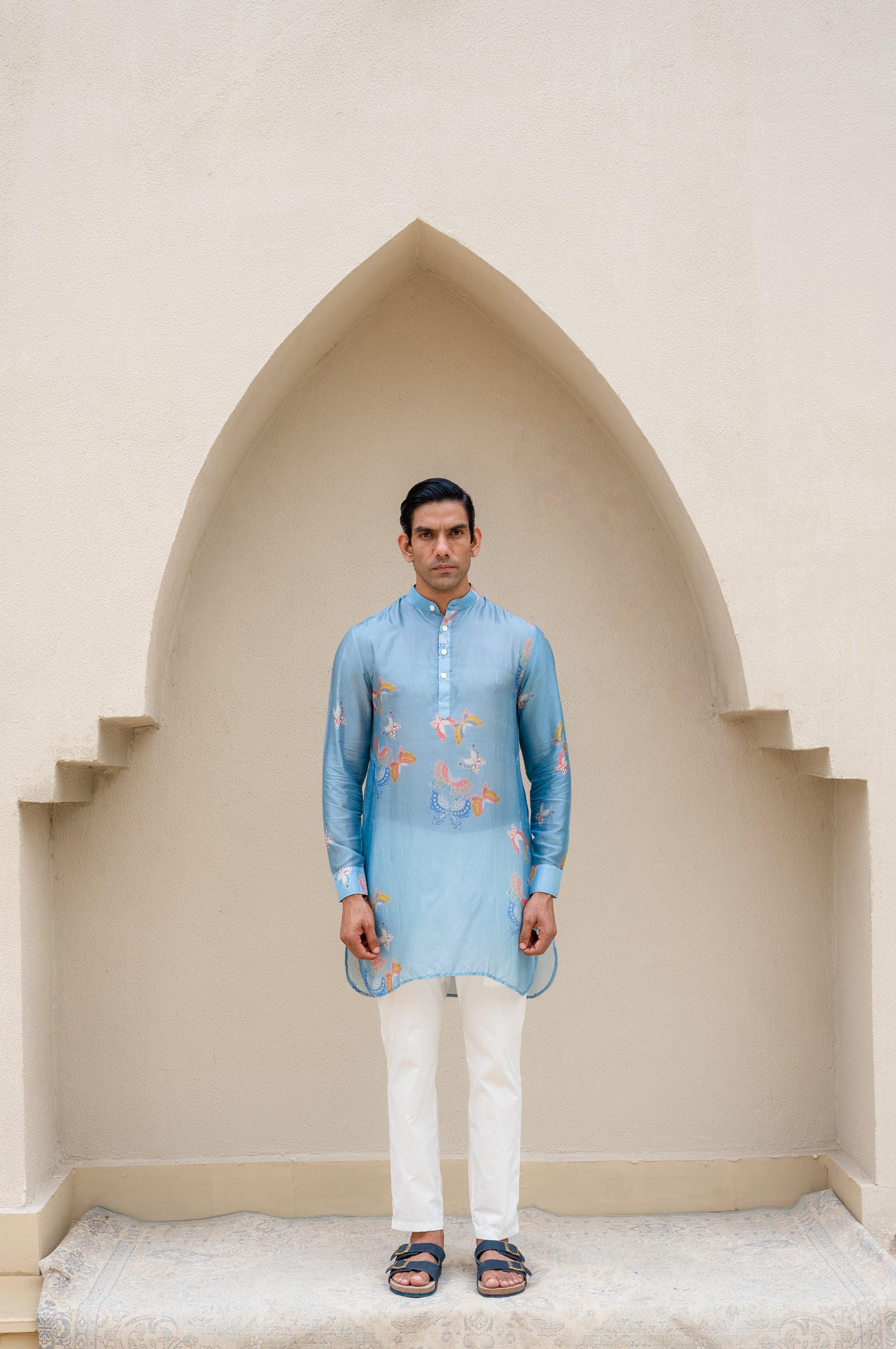 Men's printed kurta with butterfly design in light blue, worn with white trousers for a stylish look