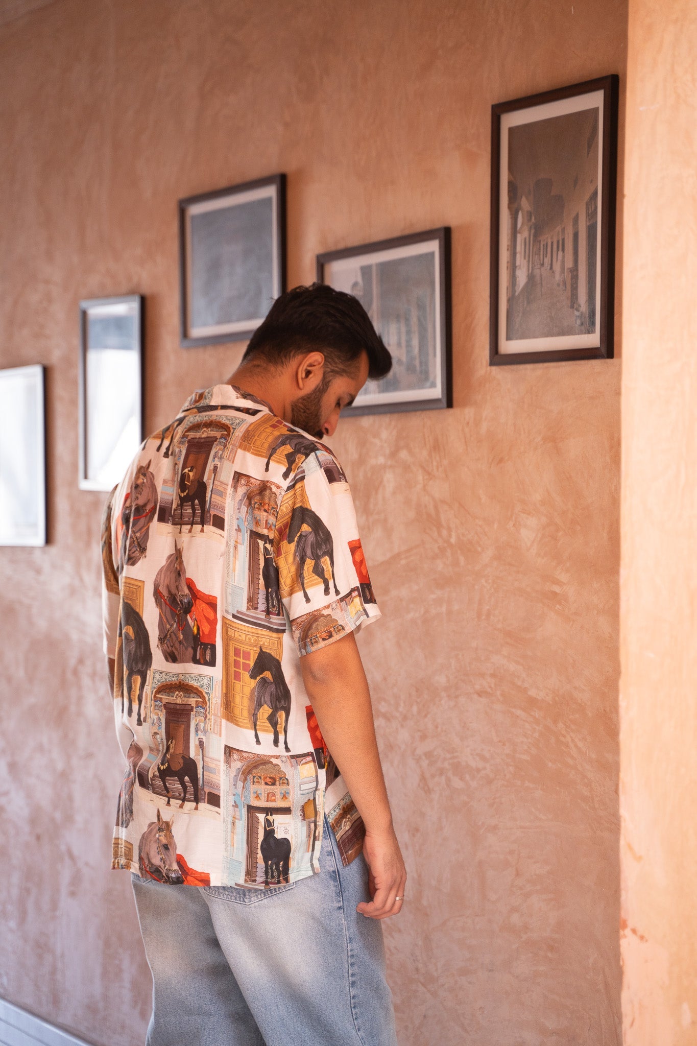 Man wearing a men's statement oversized shirt with a colorful graphic print, styled casually indoors
