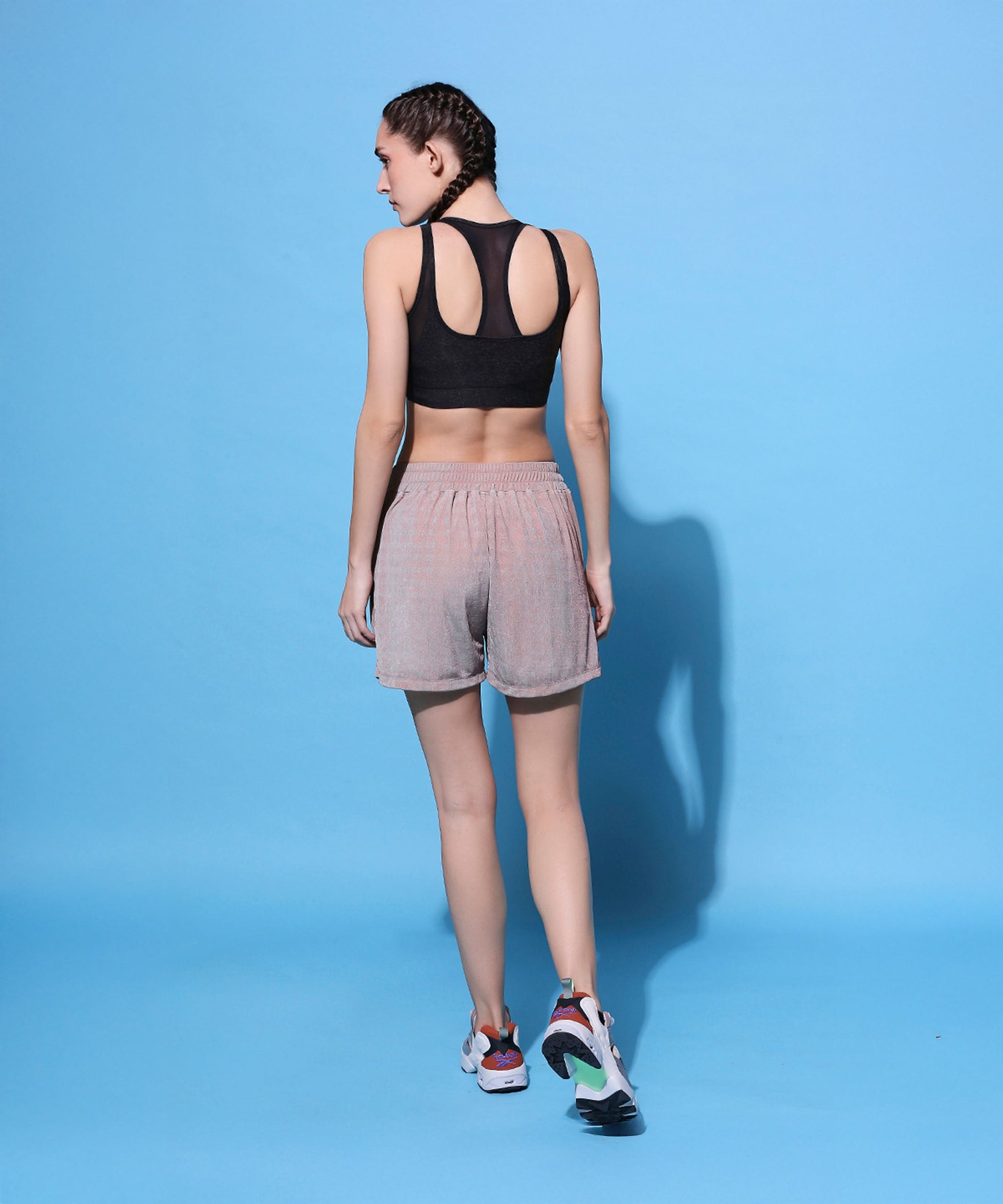 Back view of metallic tie-up shorts for women paired with a black crop top and stylish sneakers