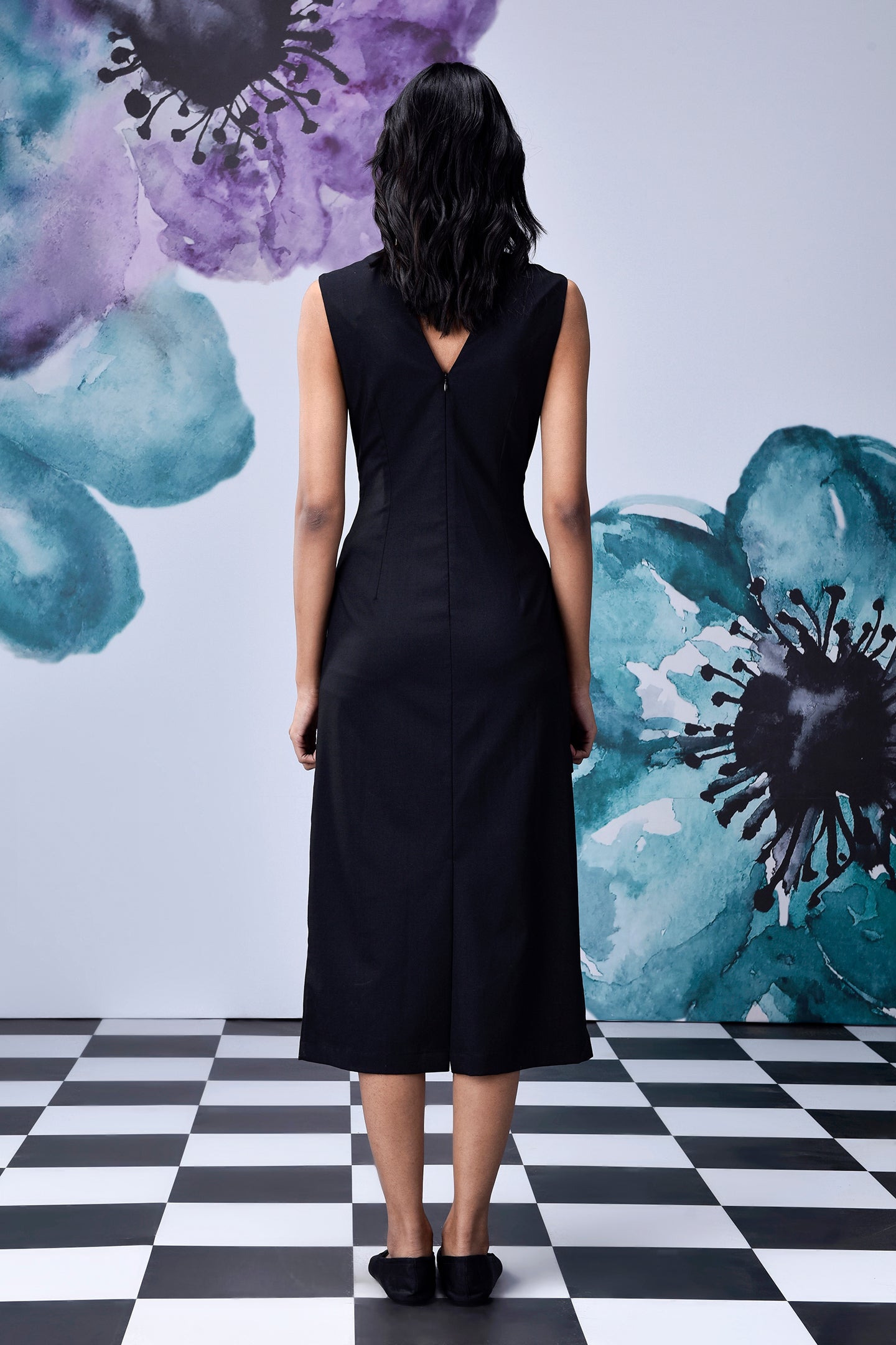 Back view of model wearing Stylera midi black dress with belt sleeveless V back mid calf length