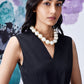 Model wearing Stylera midi black dress with belt V neck sleeveless style and pearl necklace