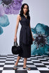 Stylera model wearing midi black dress with belt side tie V neck sleeveless with pearl necklace and black handbag