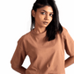 Woman wearing Stylera mocha oversized crop top paired with gray jeans against white background