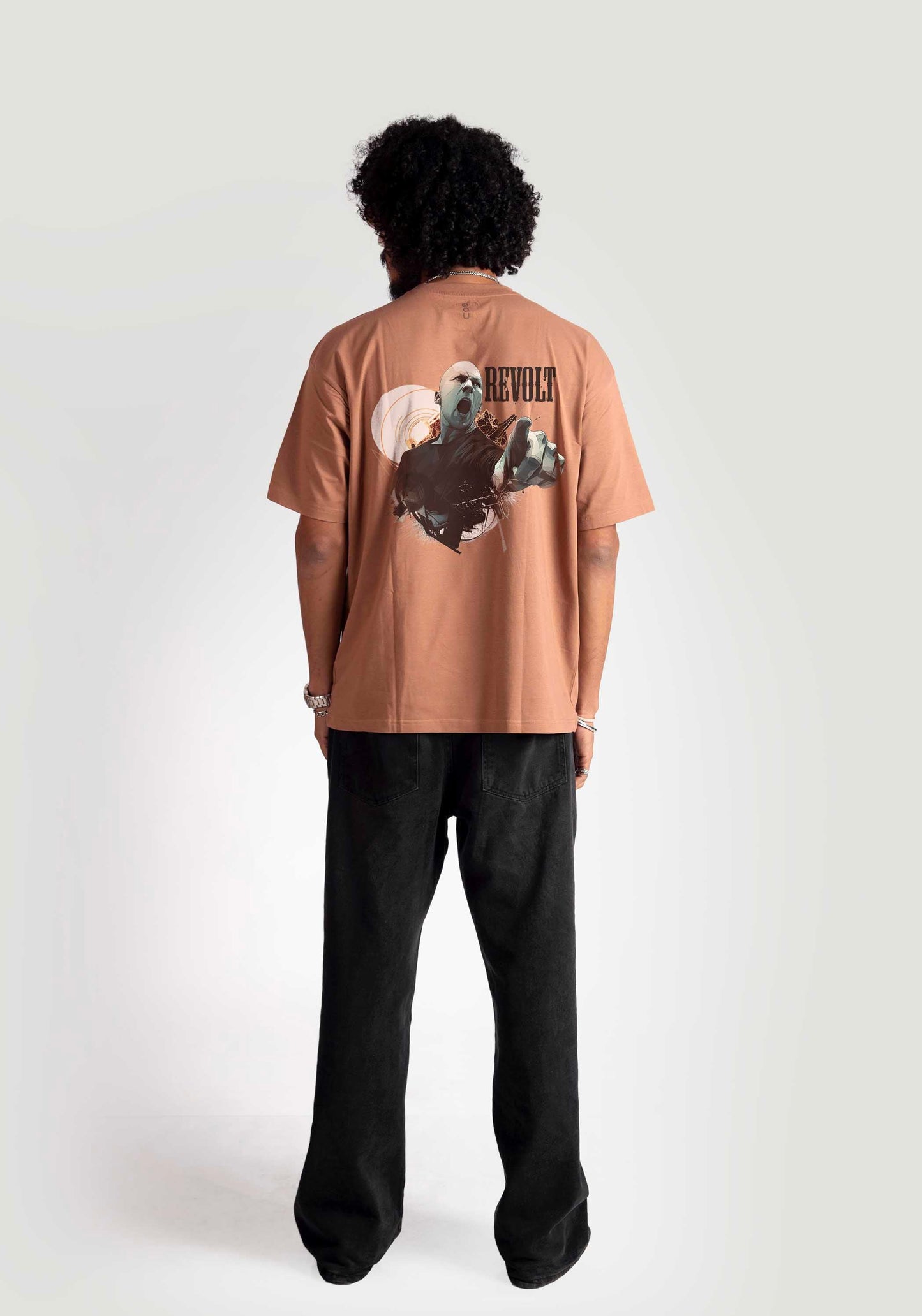 Back view of model wearing Stylera mocha oversized t-shirt with graphic design and black pants